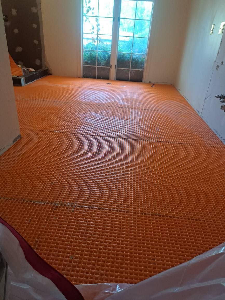 Orange underfloor heating system installed in a room, ready for flooring.
