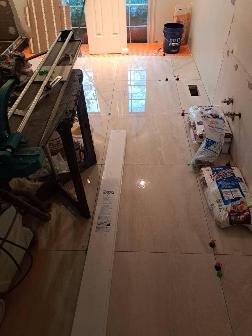 Tiled floor installation in progress, with tiles laid out, spacers, and tools.