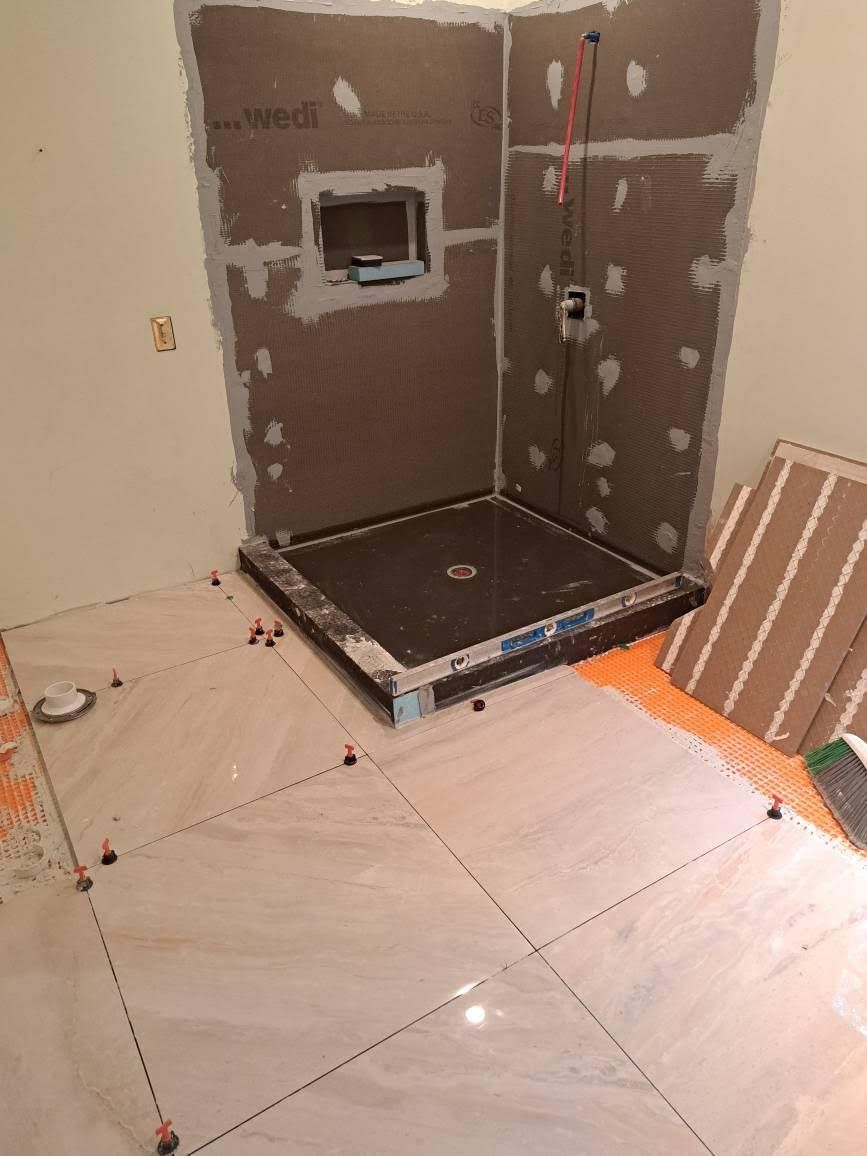 Bathroom under construction with tiled floor and shower base.