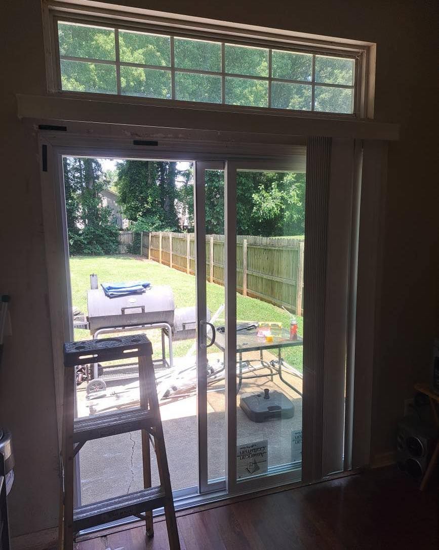 Sliding glass door leading to a backyard patio with a grill and table. A step ladder is in front of the door.
