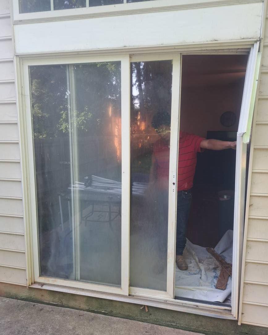 White-framed sliding glass door partially open, revealing a person in a red shirt standing inside.