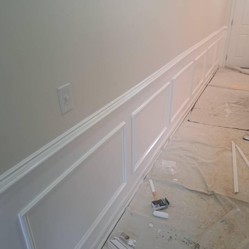 White wainscoting on a wall in a room, still under construction, with a light switch visible.