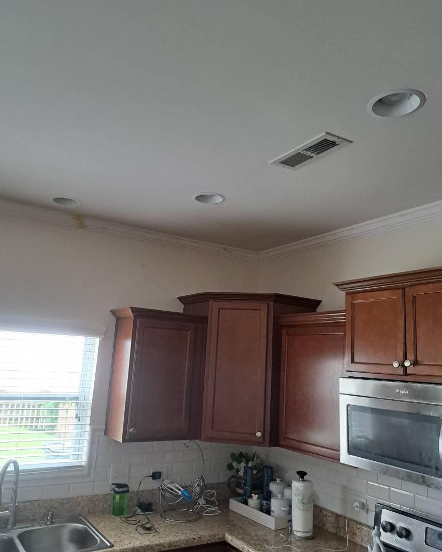 Kitchen with brown cabinets, stainless steel appliances, and white ceiling with recessed lights and crown molding.
