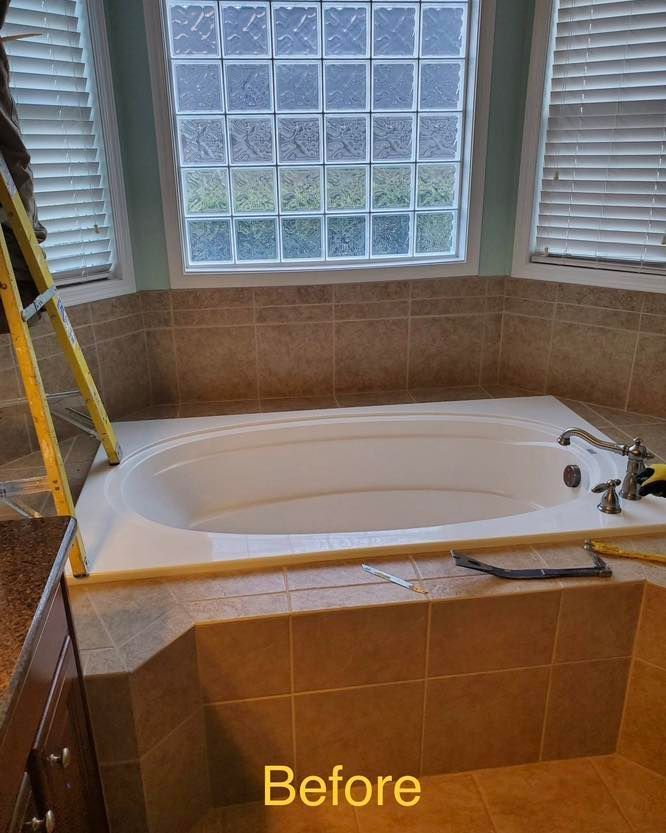 Bathroom with oval tub, tan tile surround, and glass block window. Before renovation.