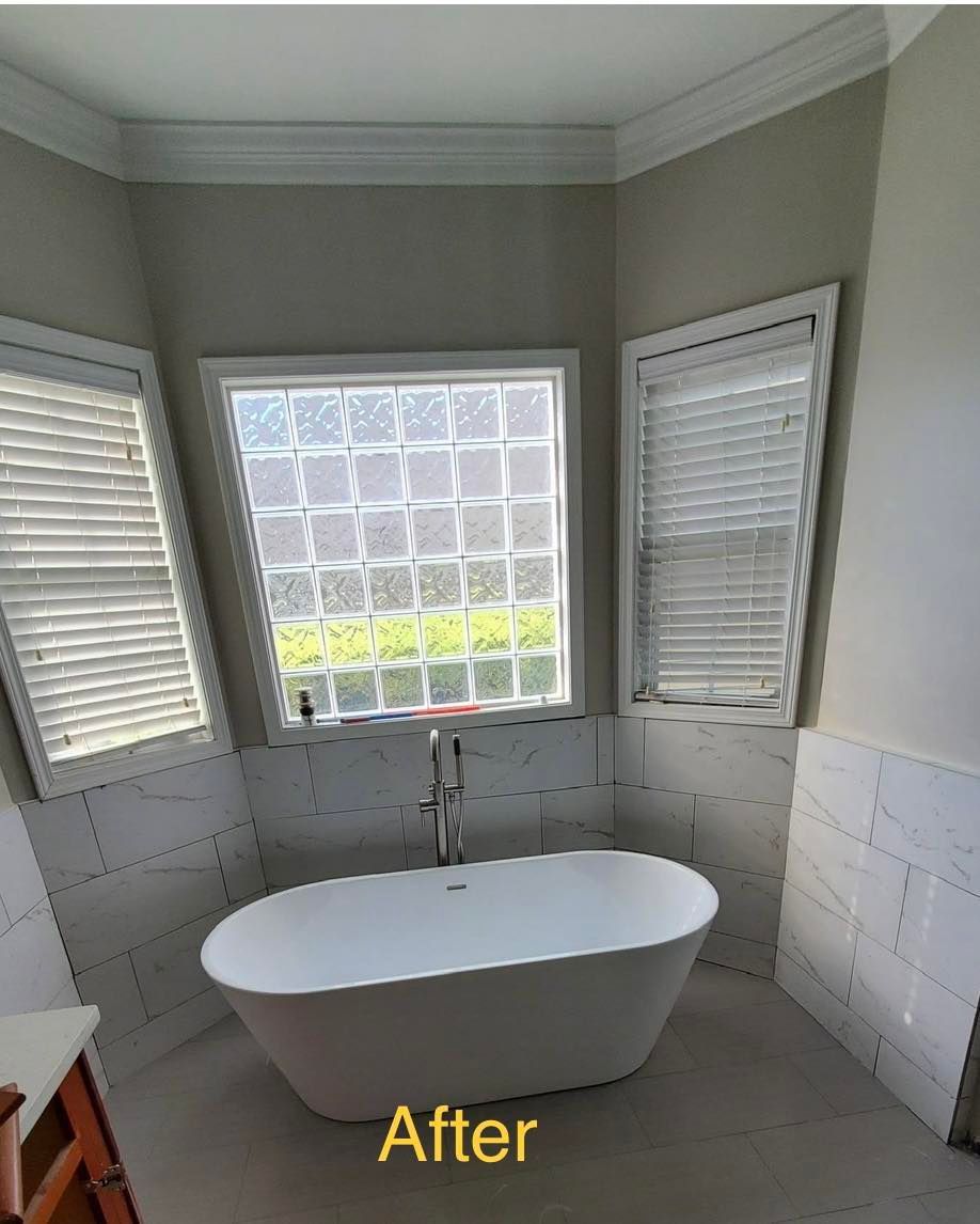 Newly renovated bathroom with oval tub, tile walls, and three windows.
