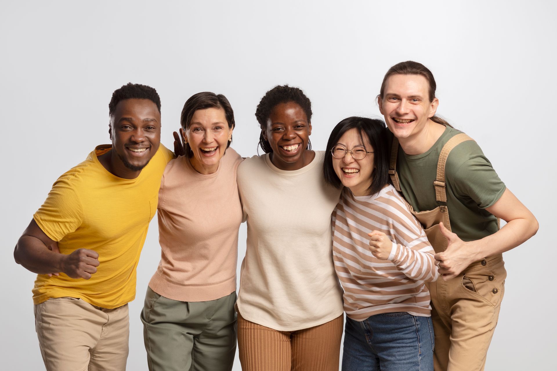 Five diverse people smiling and embracing, standing together against a white backdrop.