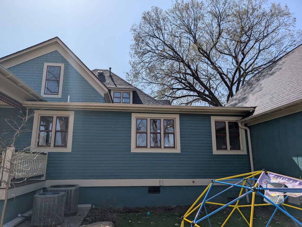 A blue house with a monkey bars in front of it.