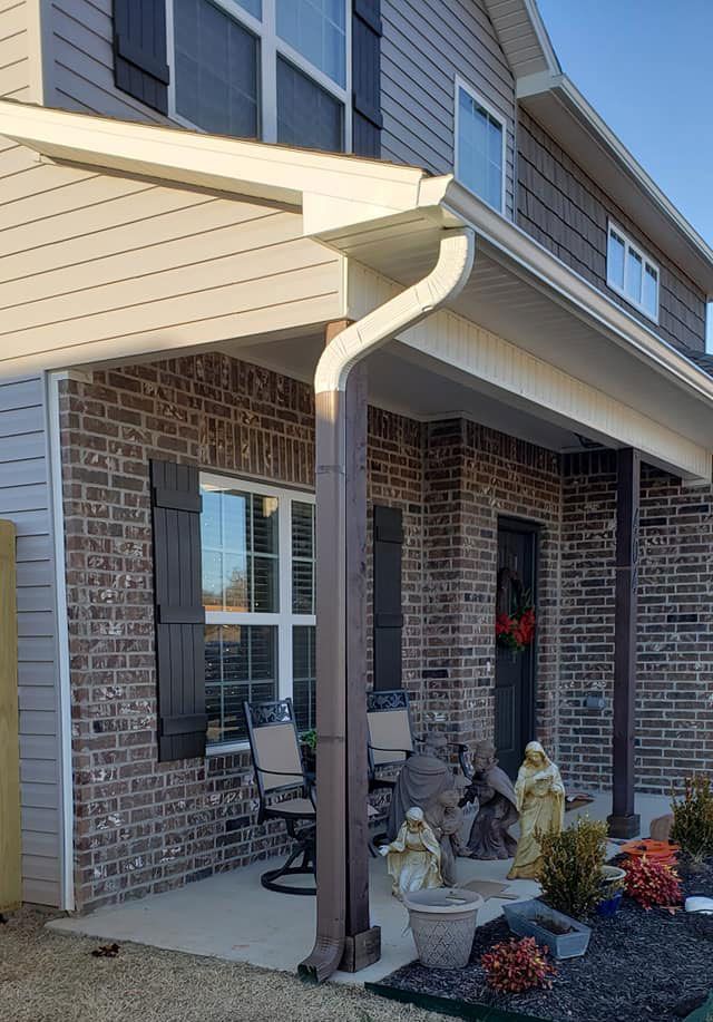 A brick house with a porch and a gutter on the side of it.