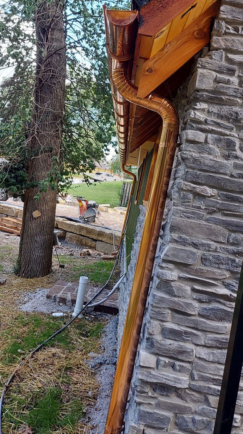 A new downspout was attached to the side of a stone building.