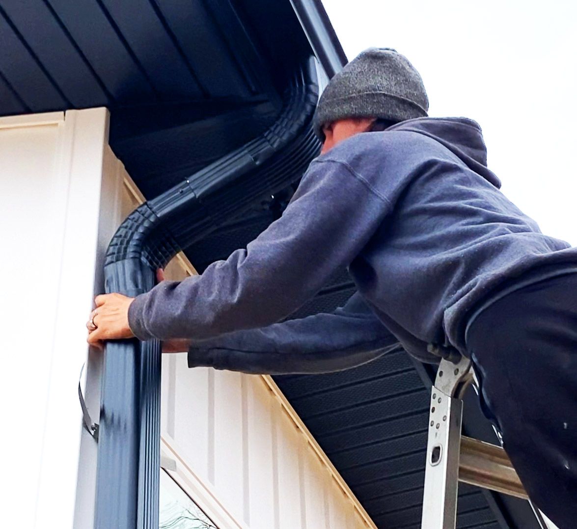 Hog trough employee putting in a downspout 