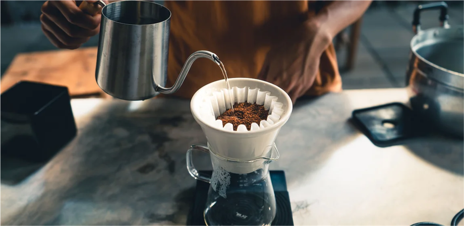 A person is pouring water into a coffee filter on a table.