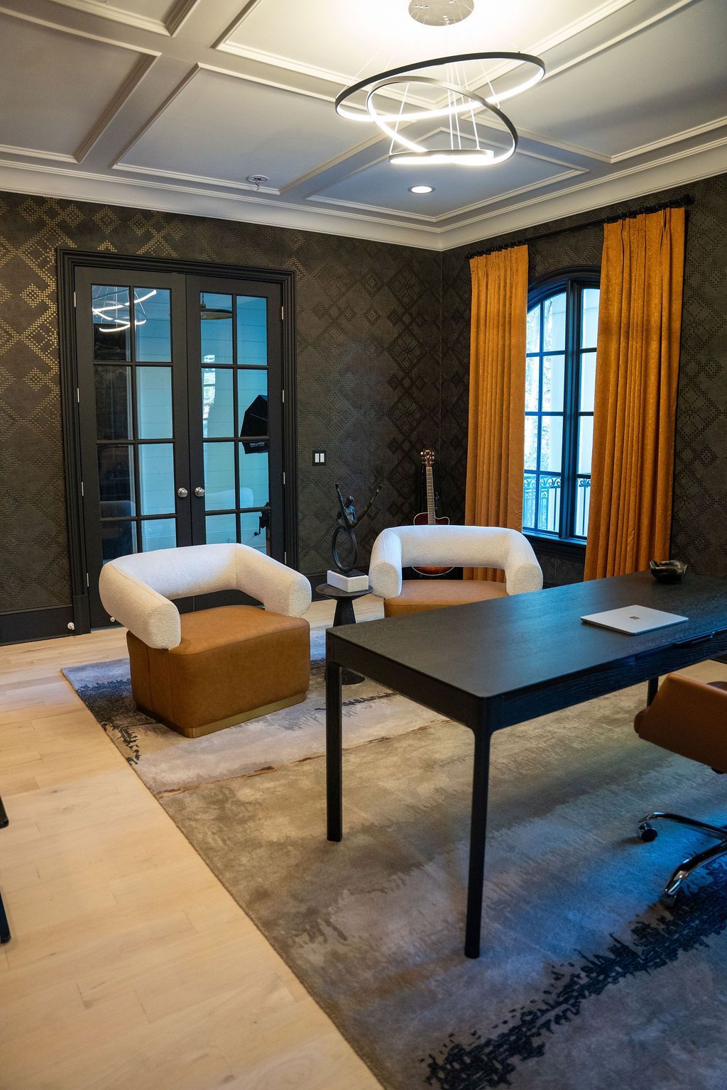 Office interior with black walls, a black desk, two armchairs, and golden curtains.