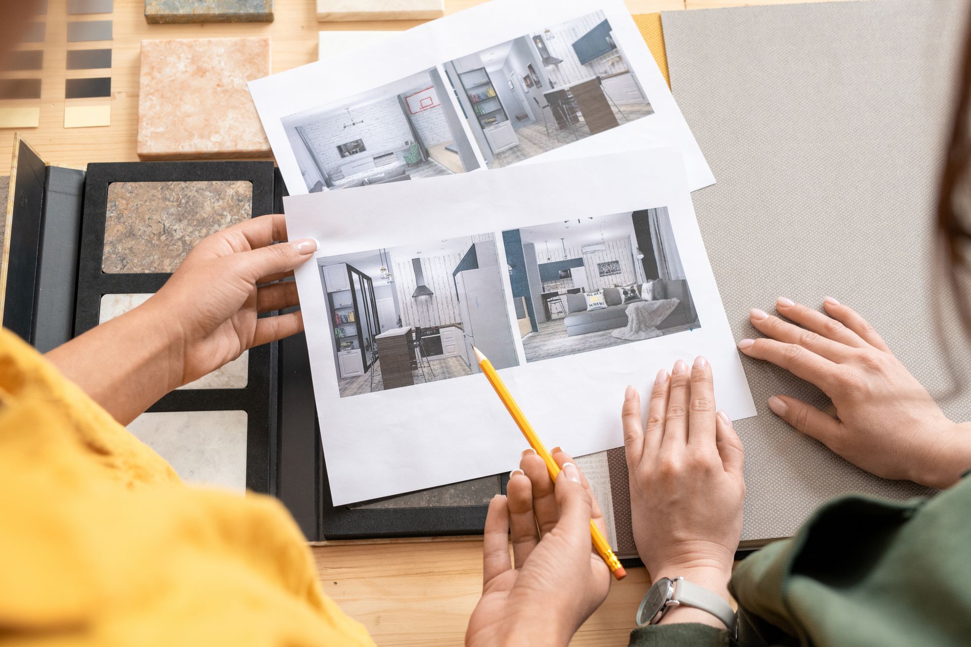 Two people looking at interior design photos, holding a pencil, with color swatches on a table.