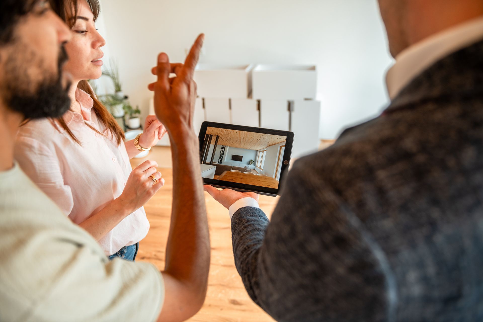 Real estate agent showing a couple a virtual tour on a tablet in an empty room.