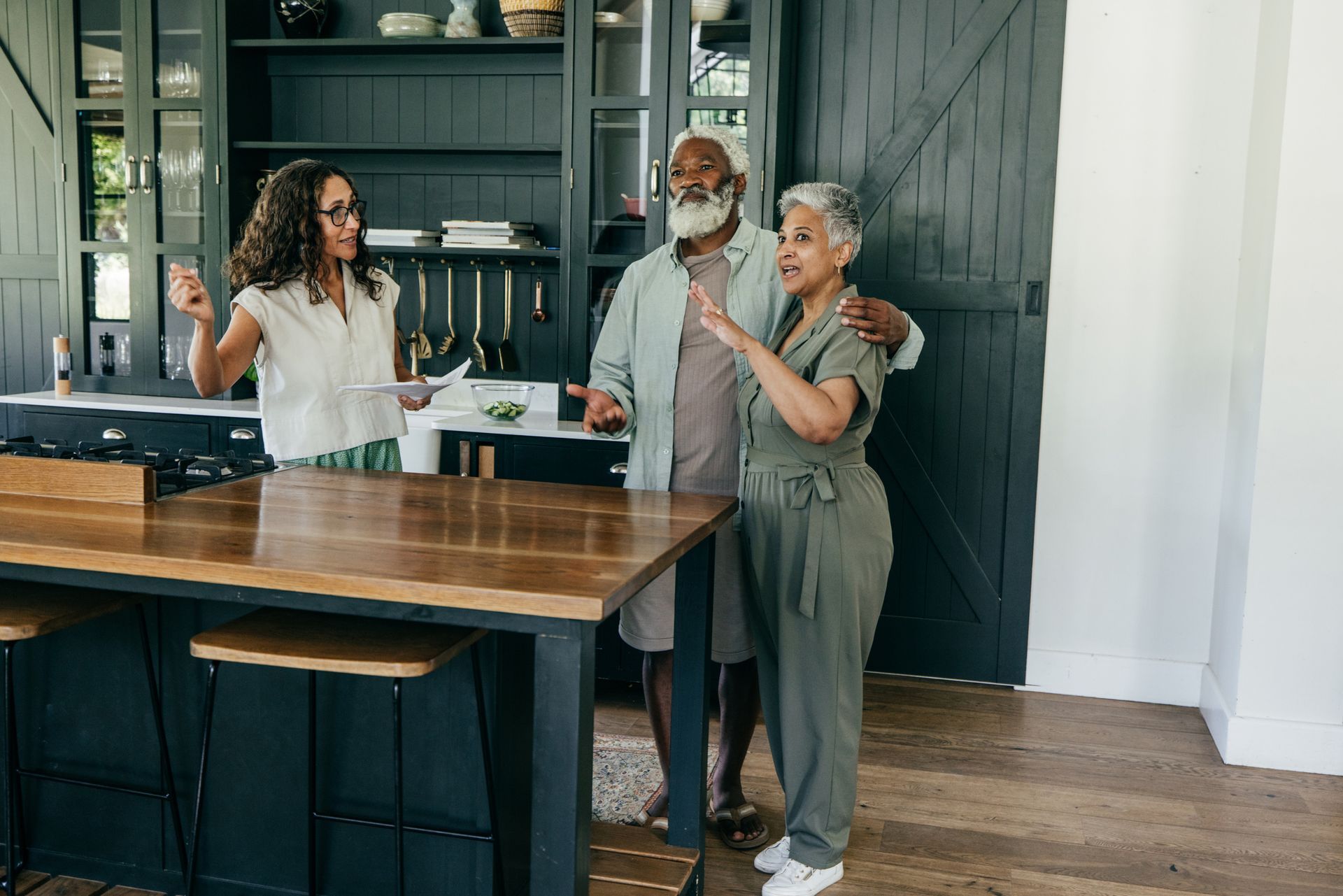 Woman in showroom looks at fabric samples, smiling. Other customers and furniture visible.
