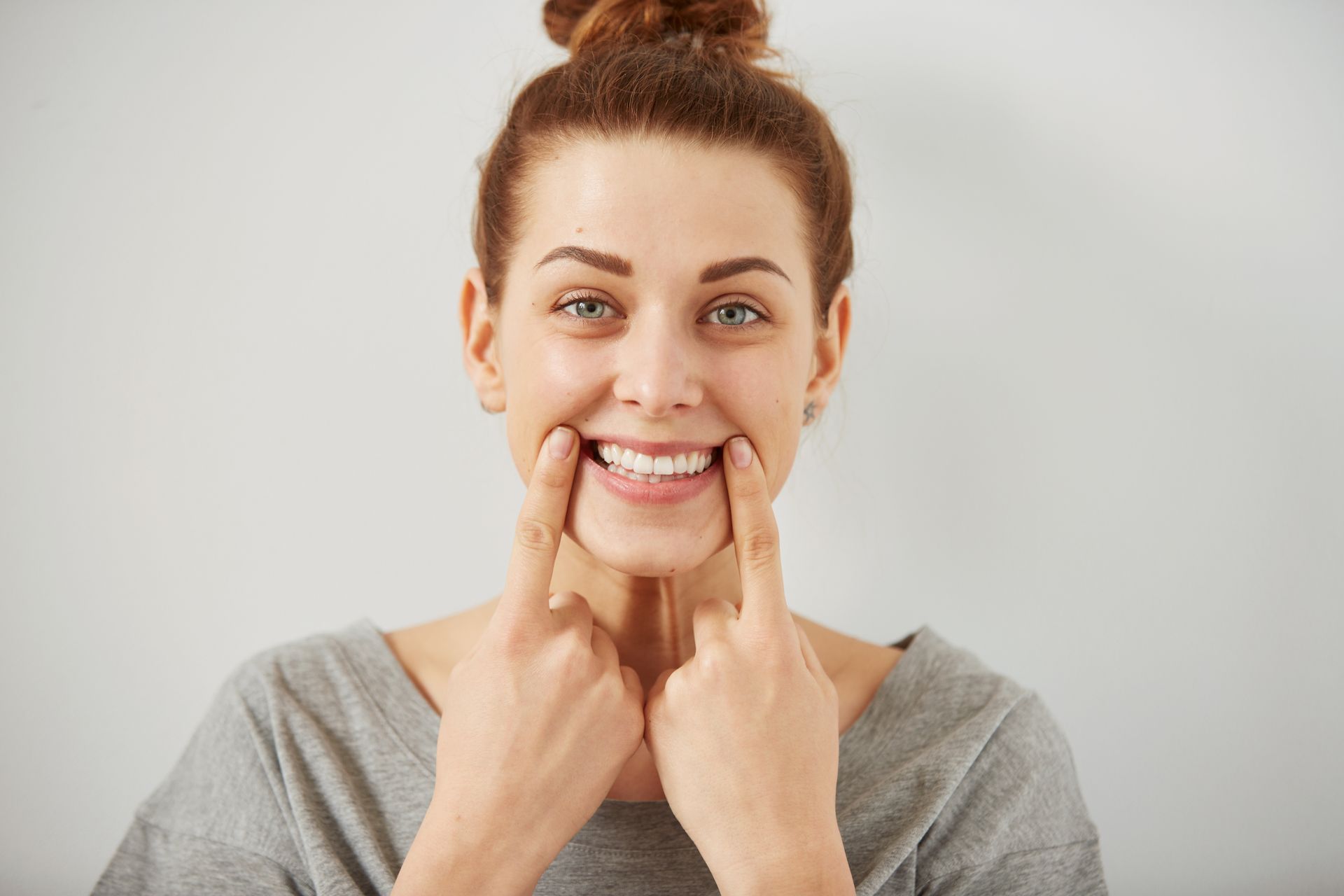 A woman is pointing at her teeth and smiling.