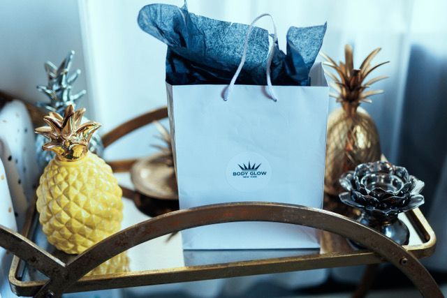 A white bag is sitting on a tray next to pineapples.