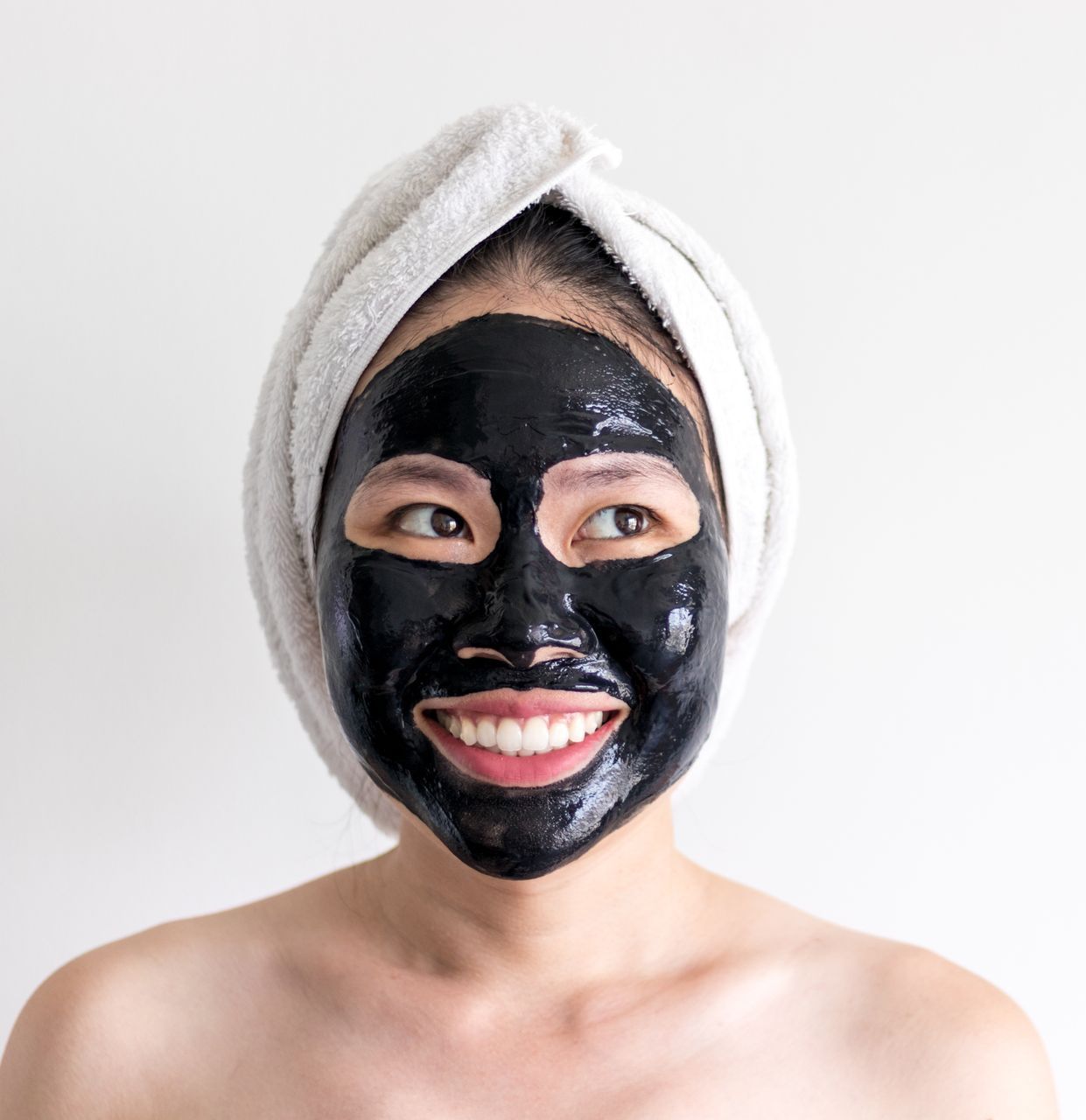 A woman is getting a black mask on her face.