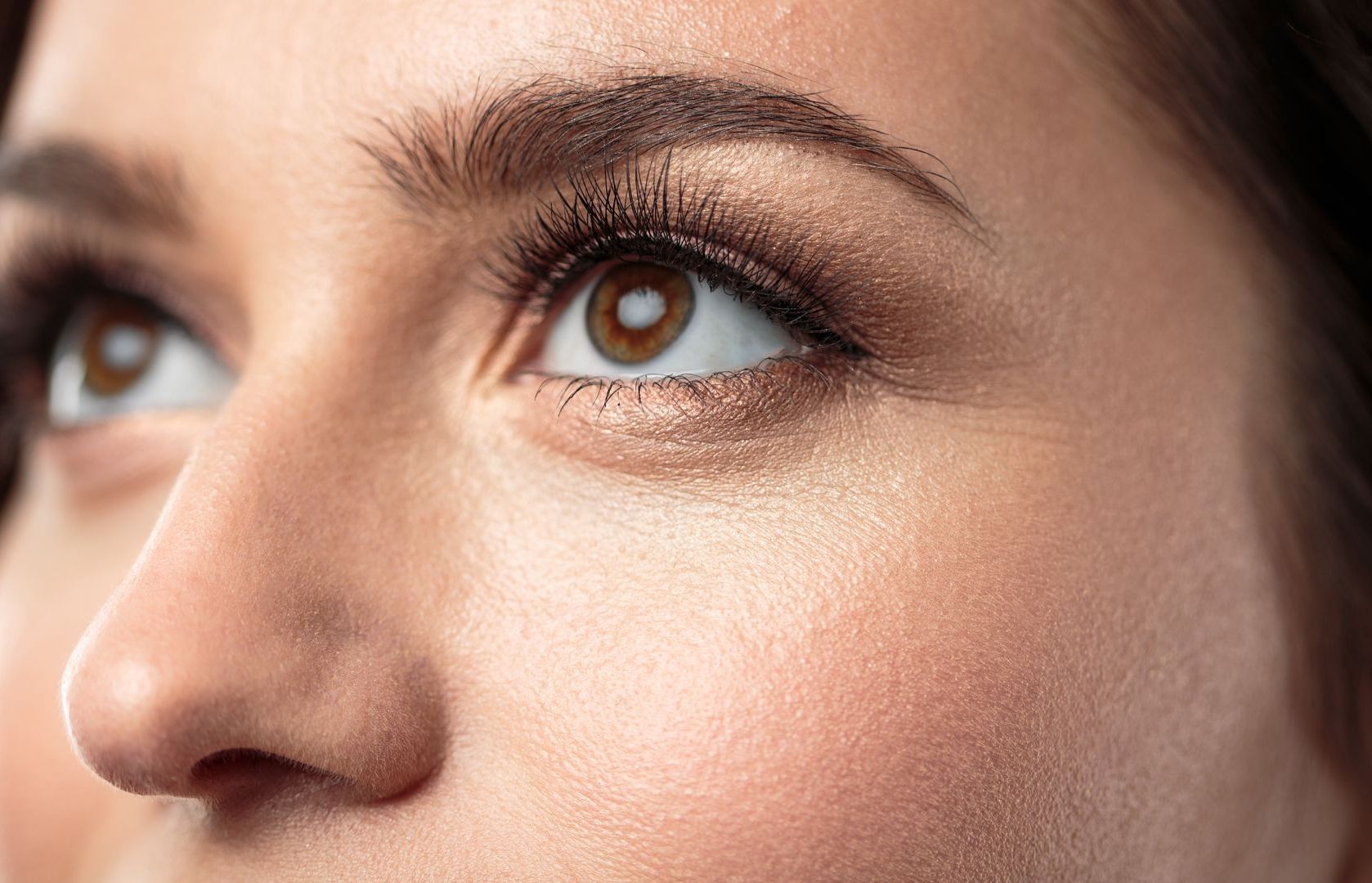 A close up of a woman 's face with her eyes looking up.