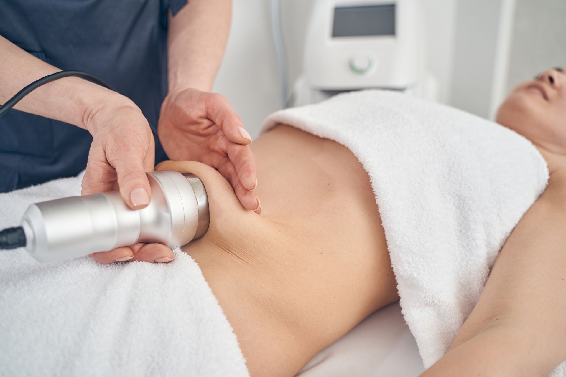 A woman is getting a cavitation treatment on her stomach.