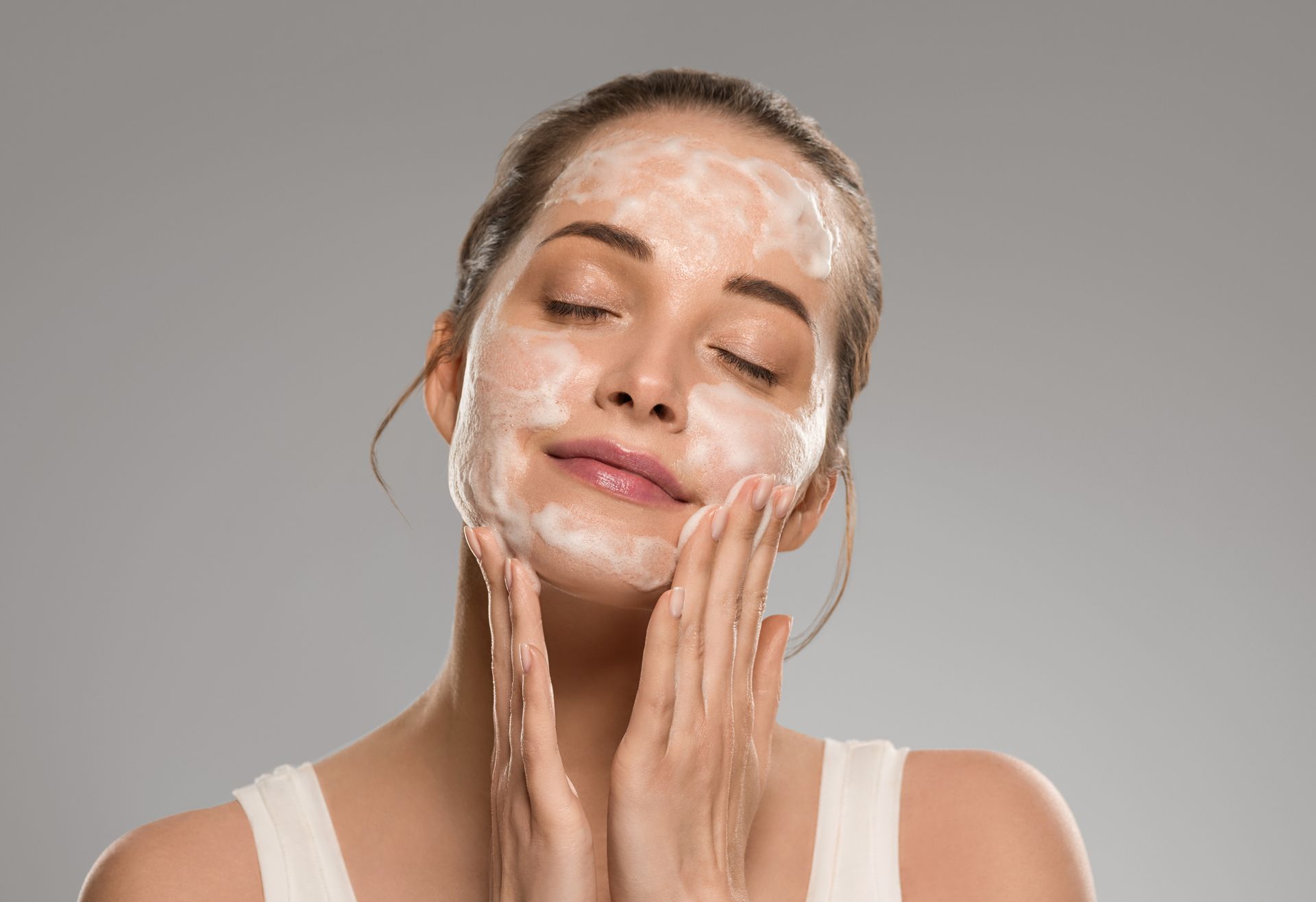 A woman is applying a facial mask to her face.