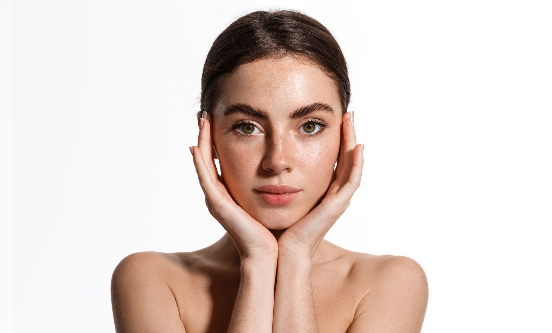 A woman with her hands on her face is looking at the camera.