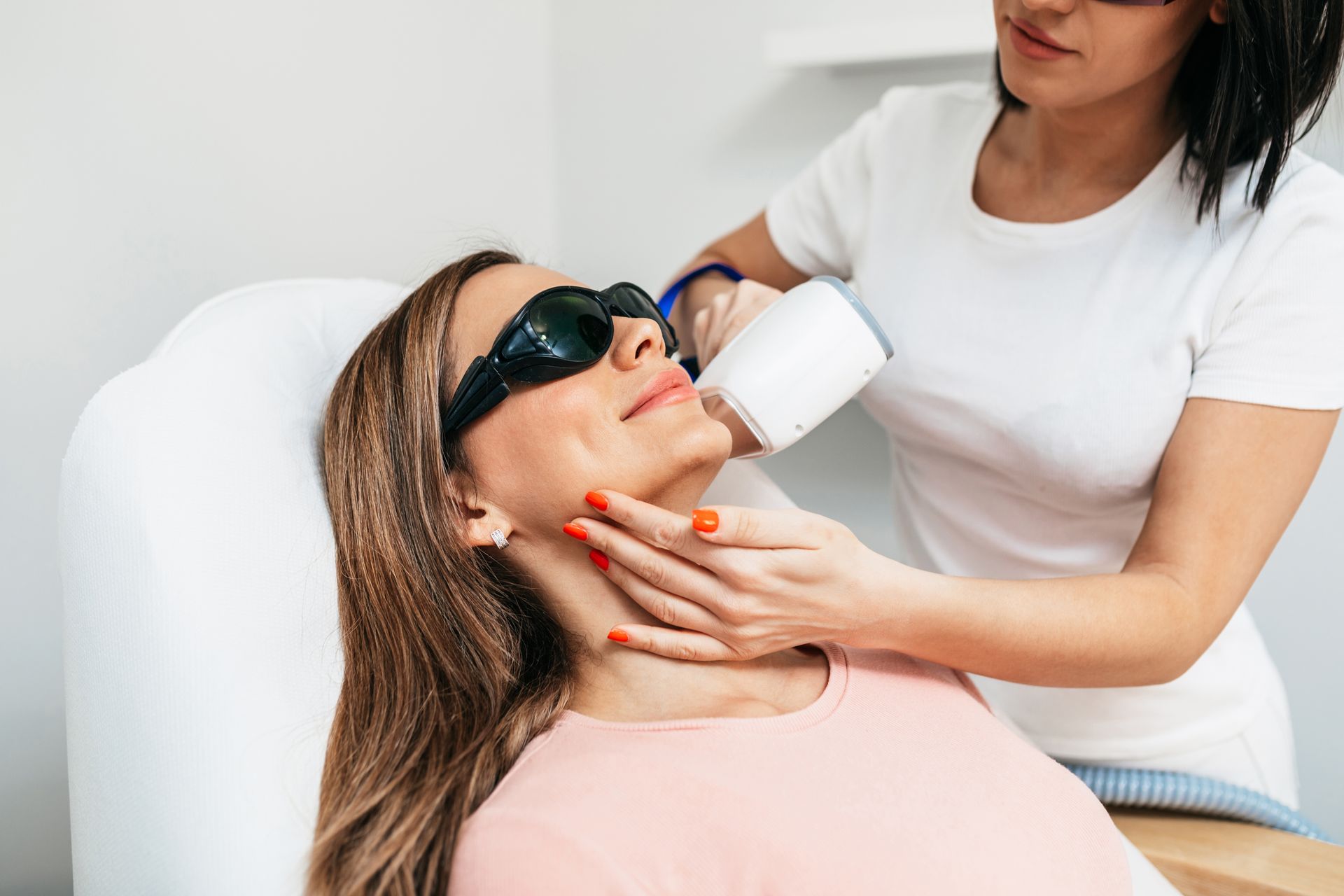 A woman is getting a laser hair removal treatment on her face.