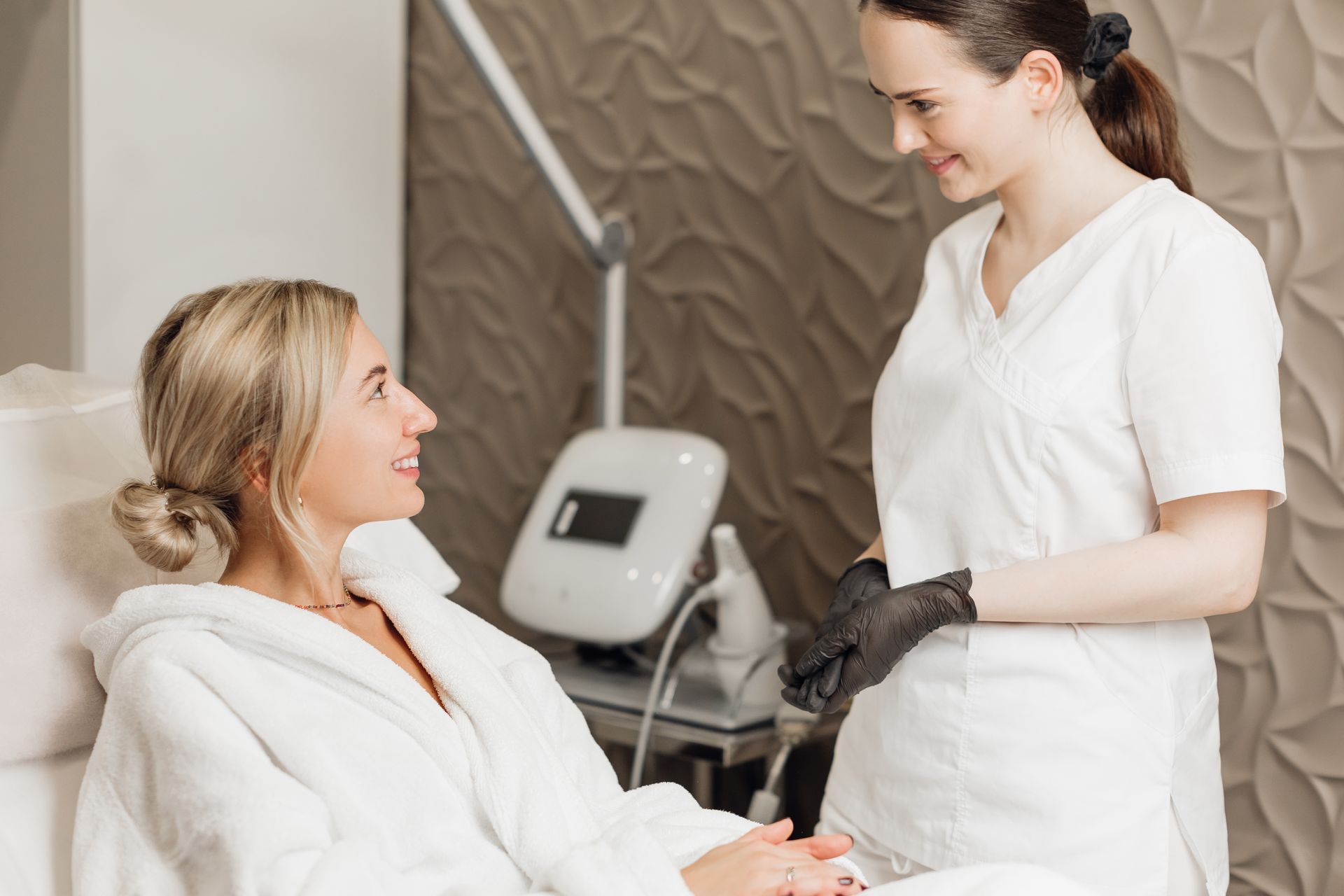 A woman is sitting in a chair talking to a nurse in a beauty salon.