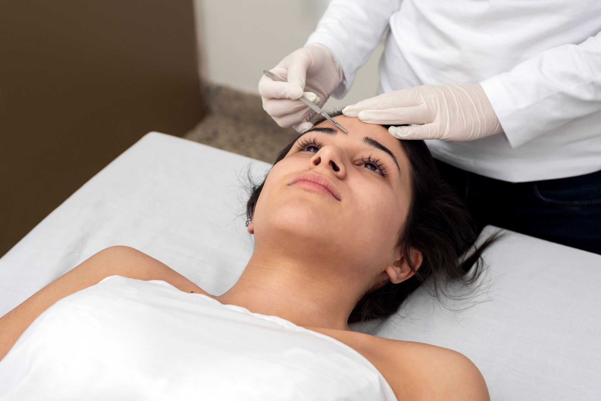 A woman is getting a botox injection in her forehead.