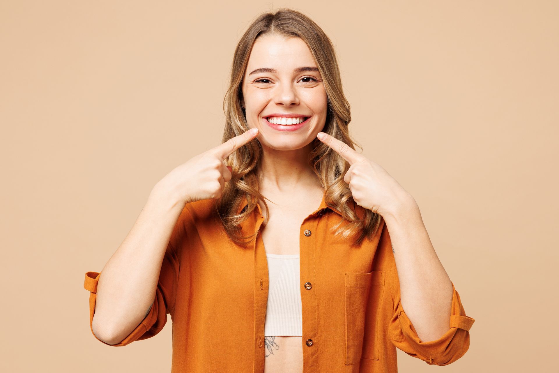 A woman is pointing at her teeth and smiling.