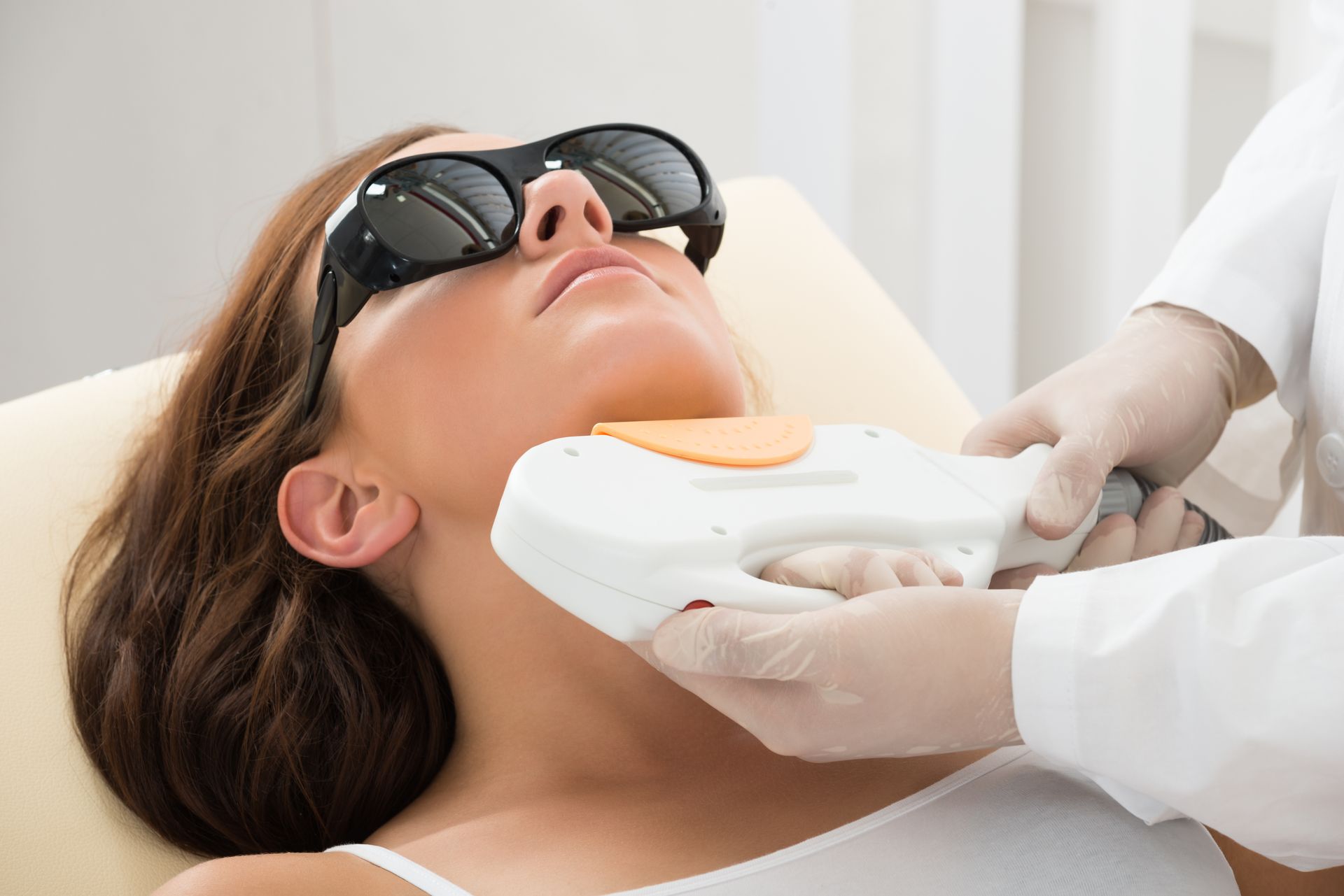 A woman is getting a laser hair removal treatment on her face.