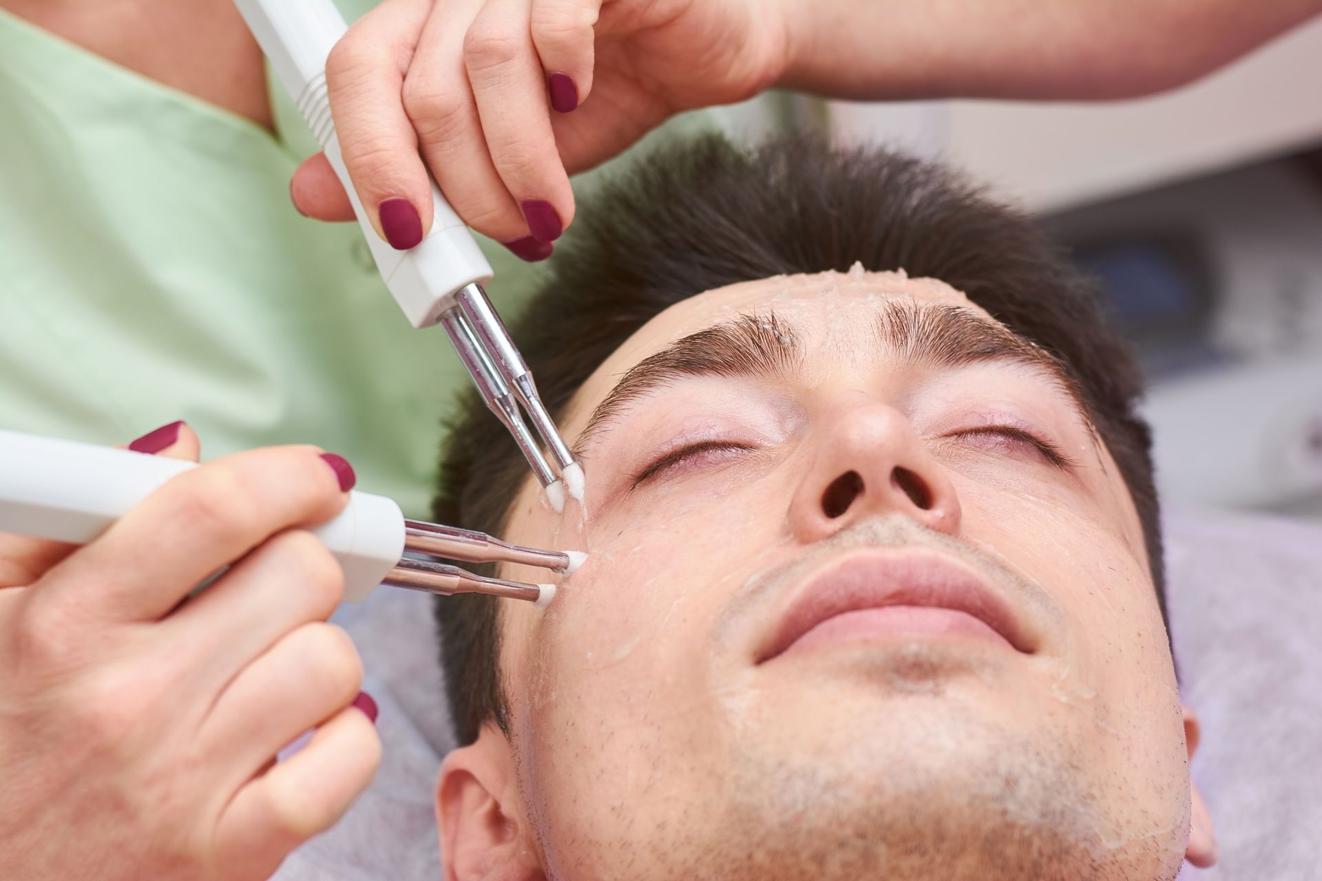 A man is getting a facial treatment at a beauty salon.