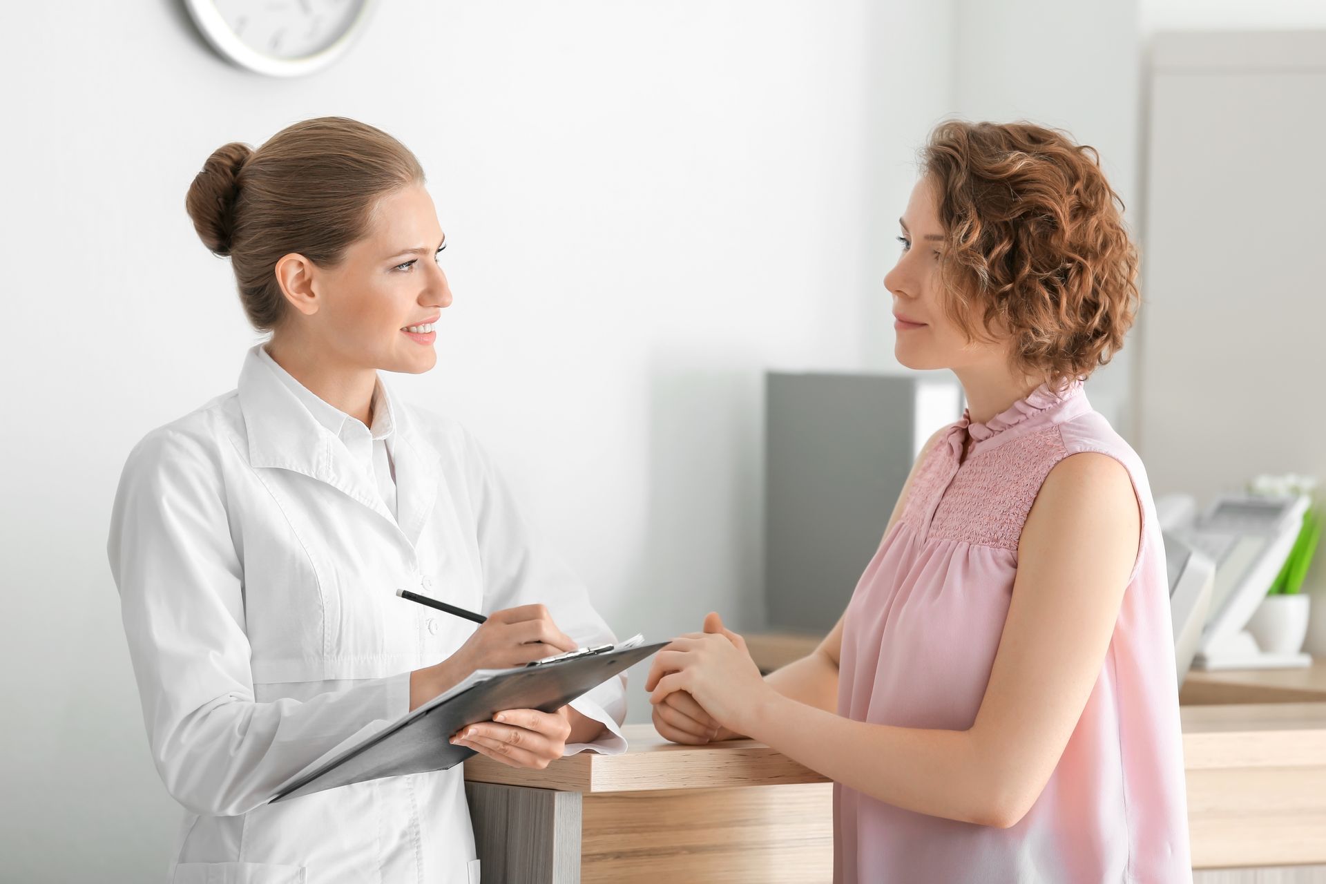 A doctor is talking to a patient at a reception desk in a hospital.