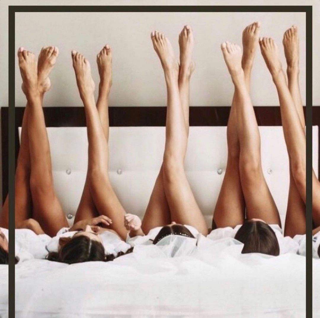 Five people lying in a bed with legs raised; feet and lower legs visible.