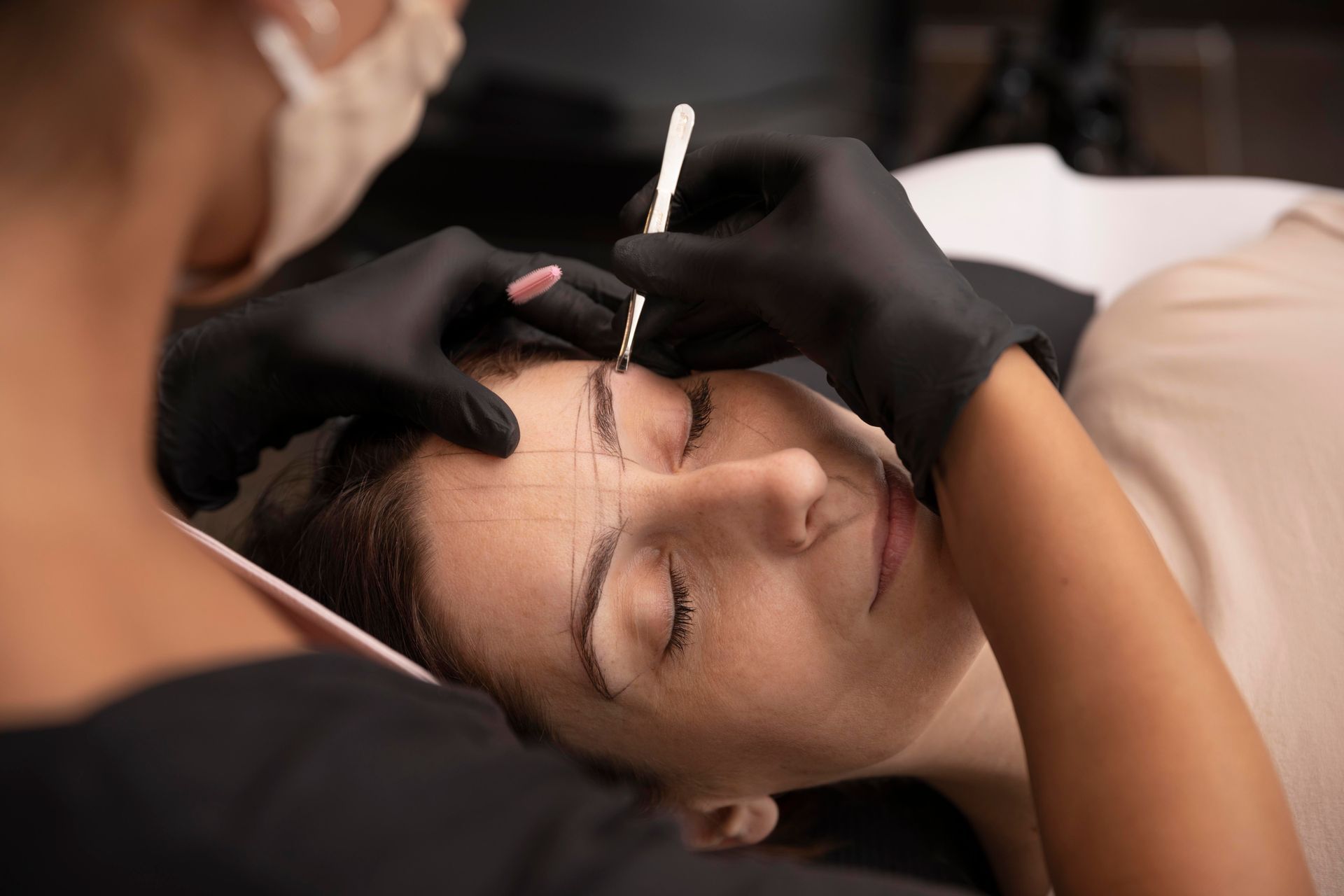 A woman is getting her eyebrows drawn by a makeup artist.