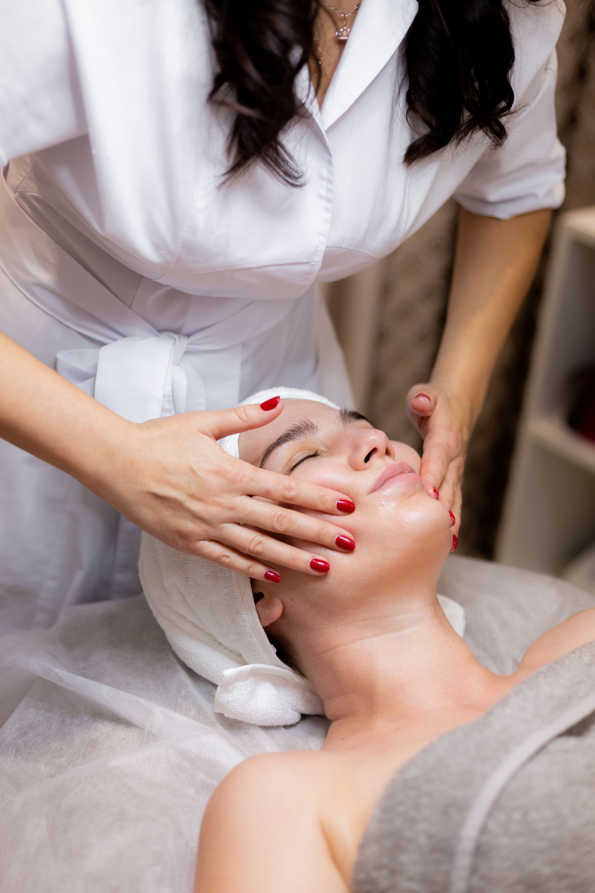 A woman is getting a facial massage at a spa.