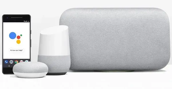 A tall black cylinder speaker next to a small, patterned spherical speaker on a white counter with a plant.