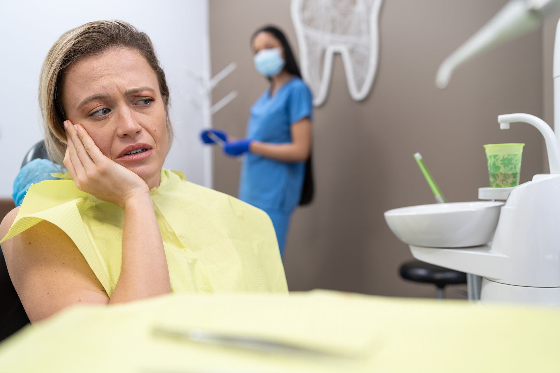 Woman with toothache in dental chair receiving care from an emergency dentist at the clinic.