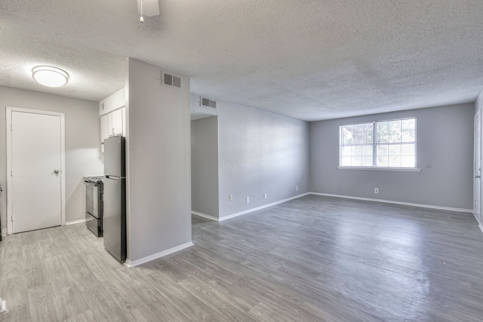 Photo of a kitchen, dining area and a living room, as well as a hallway entrance