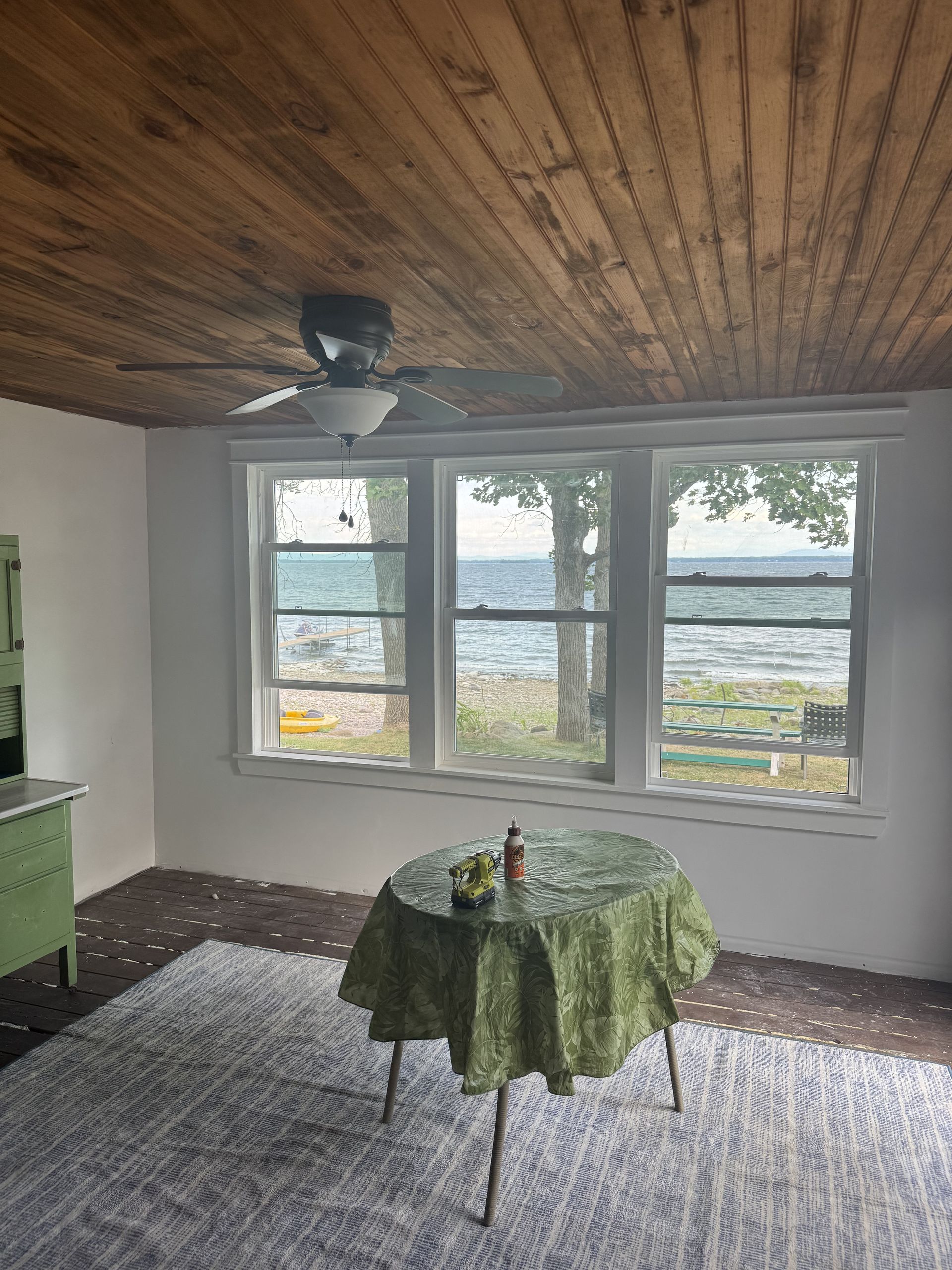 Interior room with a table, windows facing water, and a wood ceiling.
