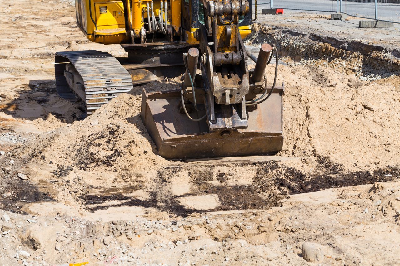 A yellow excavator is moving dirt on a construction site.