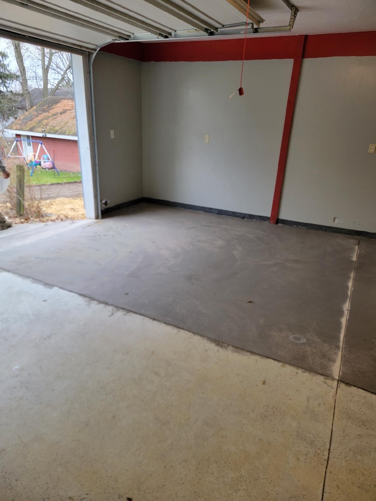 An empty garage with white cabinets and a garage door open.