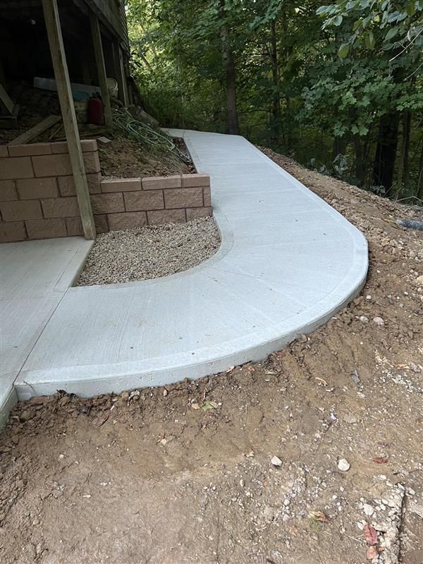 A concrete walkway is being built next to a brick wall.