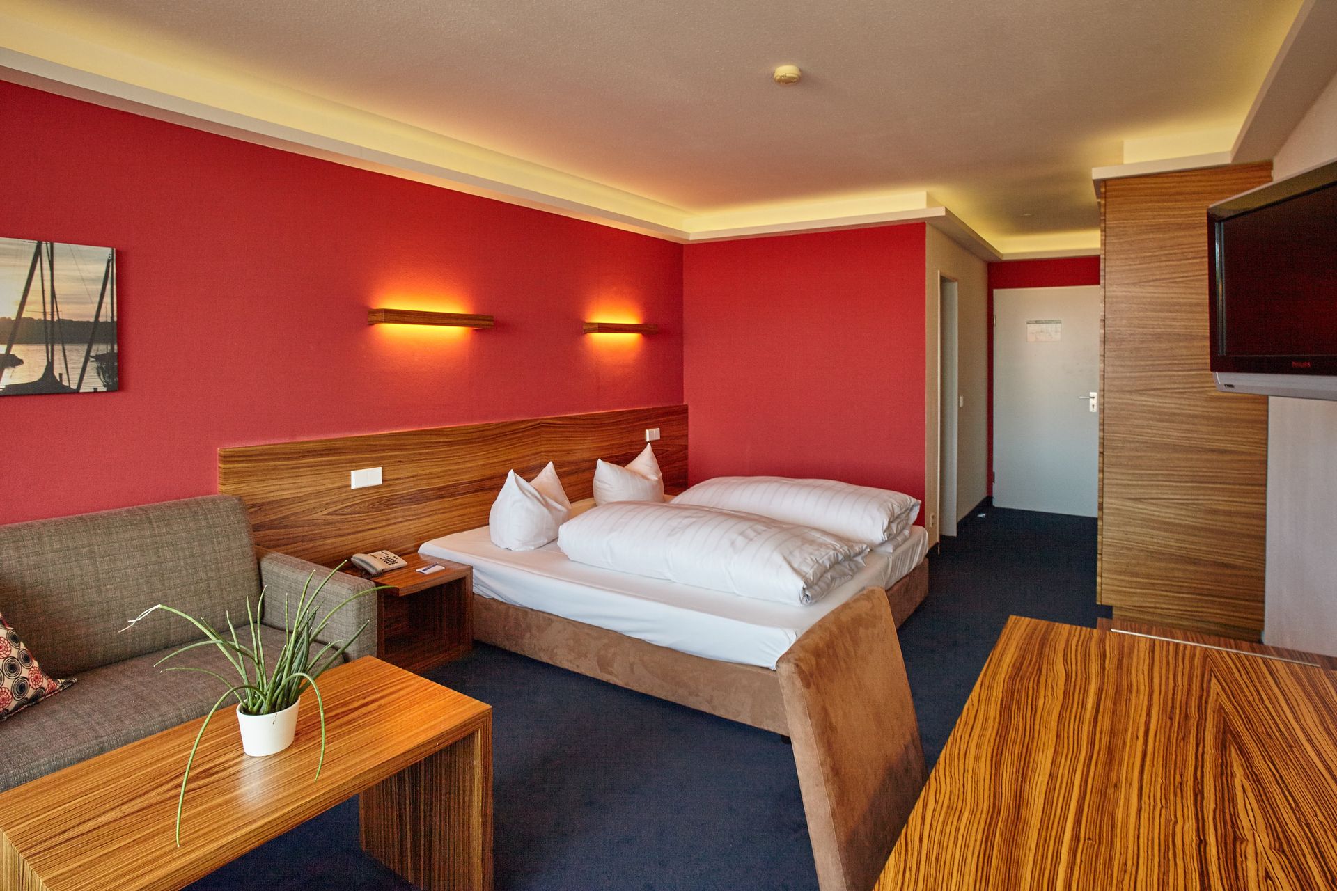 Ein Hotelzimmer mit zwei Betten, einer Couch, einem Tisch und einem Fernseher.