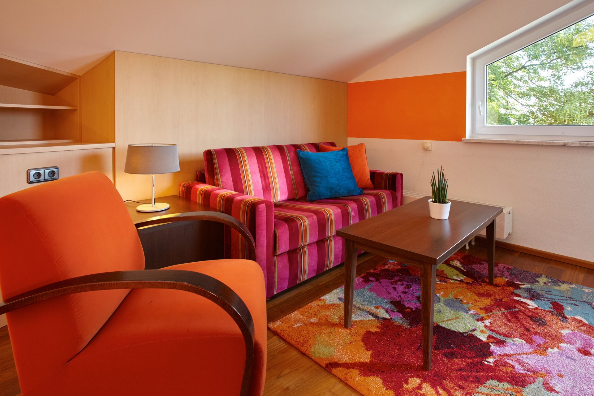 Ein Wohnzimmer mit Sofa, Sessel, Couchtisch und Teppich.