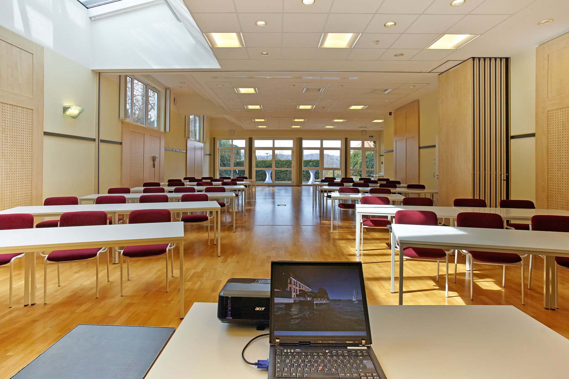 Ein großer Raum mit Tischen und Stühlen und einem Laptop auf einem Schreibtisch