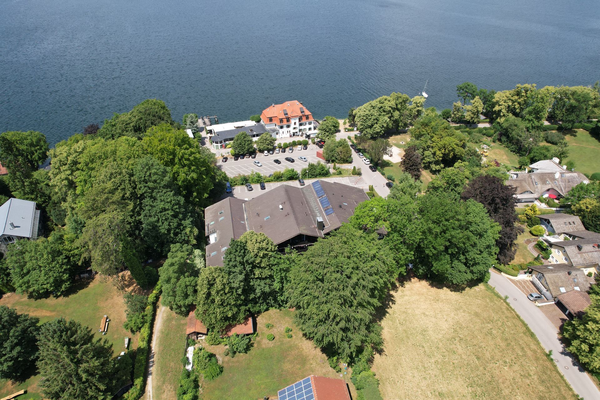 Luftaufnahme einer Hotelanlage am See, umgeben von Bäumen und Grünflächen, ideal für Seeurlaub Bayern.