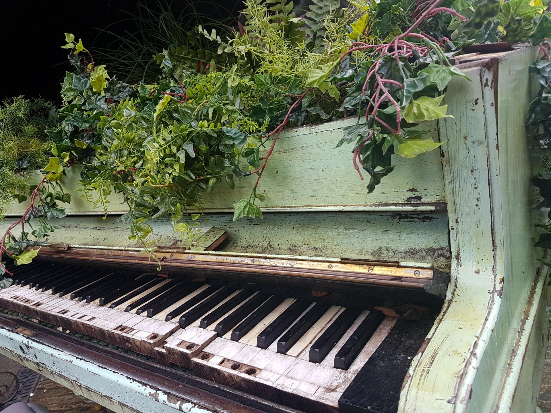 outdoor green piano with flowers growing out of top