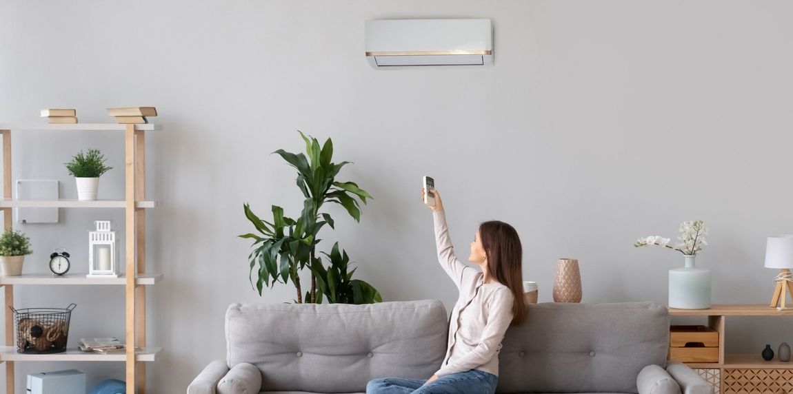 Woman Switching On Air Conditioner — Vernal, UT — Airco Heating & Cooling Inc