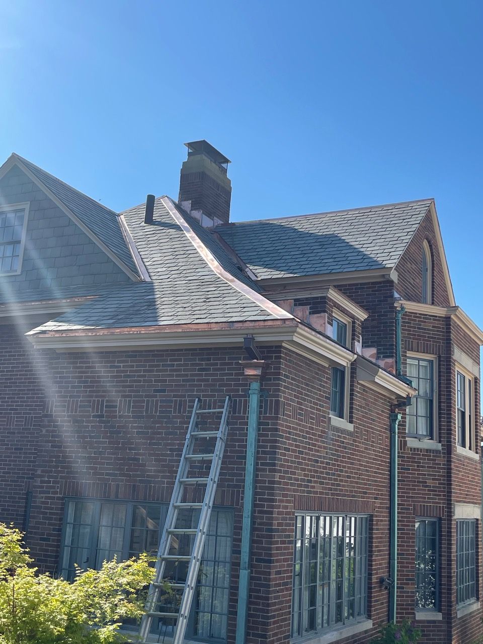 A ladder is sitting on the side of a brick house.